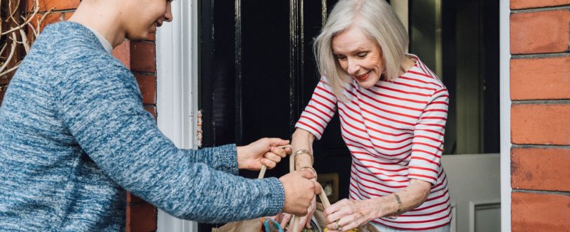 young person delivers groceries to older adult